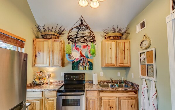 A kitchen with wooden cabinets, a stainless steel refrigerator, a stove, and a sink.