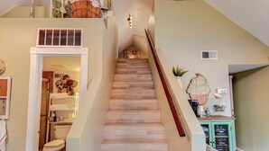 A staircase with wooden steps leading to a landing with a small table and decorative items. - 2BD Chic Cottage Mtns Walk Everywhere (Colorado Springs)