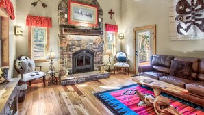 A cozy living room with a stone fireplace, leather sofa, and a colorful rug. - Mountain Getaway Cabinhot Tub & Pool Table4bd (Cascade)