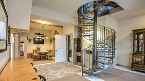 A spacious living area with a wooden dining table, a spiral staircase, and a television mounted on the wall. - Mountain Getaway Cabinhot Tub & Pool Table4bd (Cascade)