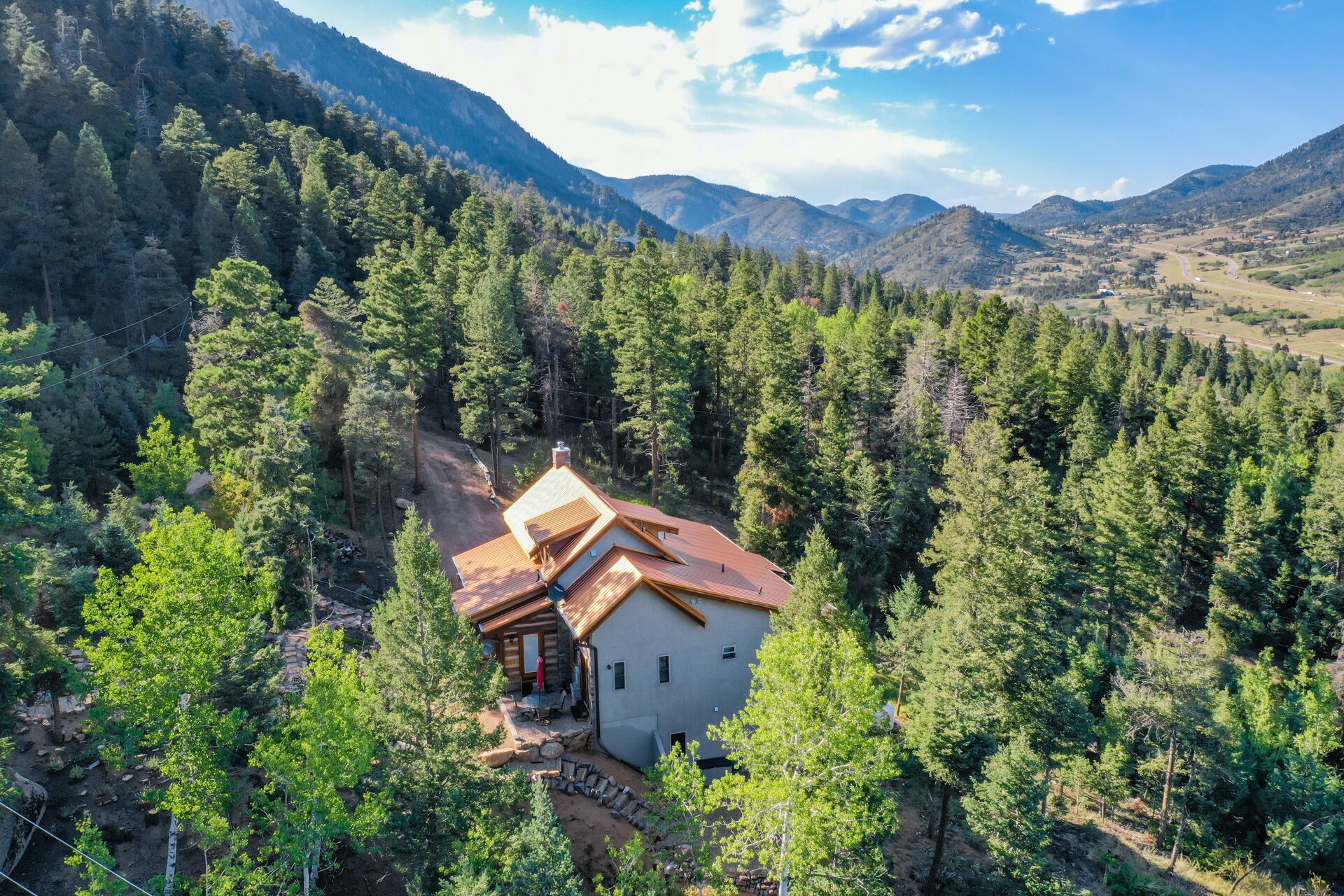 A cabin surrounded by dense forest with a clear view of the mountains in the background.