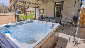 A hot tub under a covered patio with outdoor furniture and a view of a building in the background. - 3BD Downtown Modern Victorian W/hot Tub, Park & Lake! (Colorado Springs)