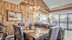 Un coin repas avec une table en bois et des chaises en cuir, un lustre et une grande fenêtre donnant sur un beau paysage.