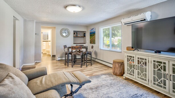 A living room with a sofa, TV, and a dining area with chairs and a table. - Modern&chic Cottage1bdcomfy Home In Old Colorado (Colorado Springs)