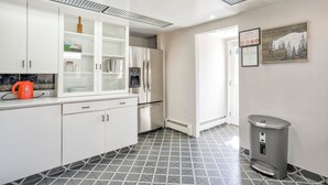 A modern kitchen with white cabinets, a stainless steel refrigerator, a coffee machine, and a trash bin. - Modern&chic Cottage1bdcomfy Home In Old Colorado (Colorado Springs)