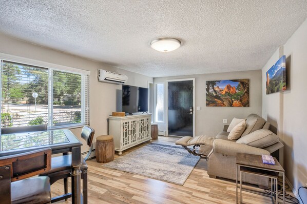 A living room with a wooden floor, a sofa, a TV, and a fireplace.