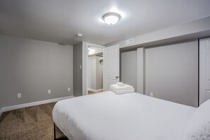 A bedroom with a bed, a closet, and a door leading to another room. - 4 Bedroom with Grill (Colorado Springs)