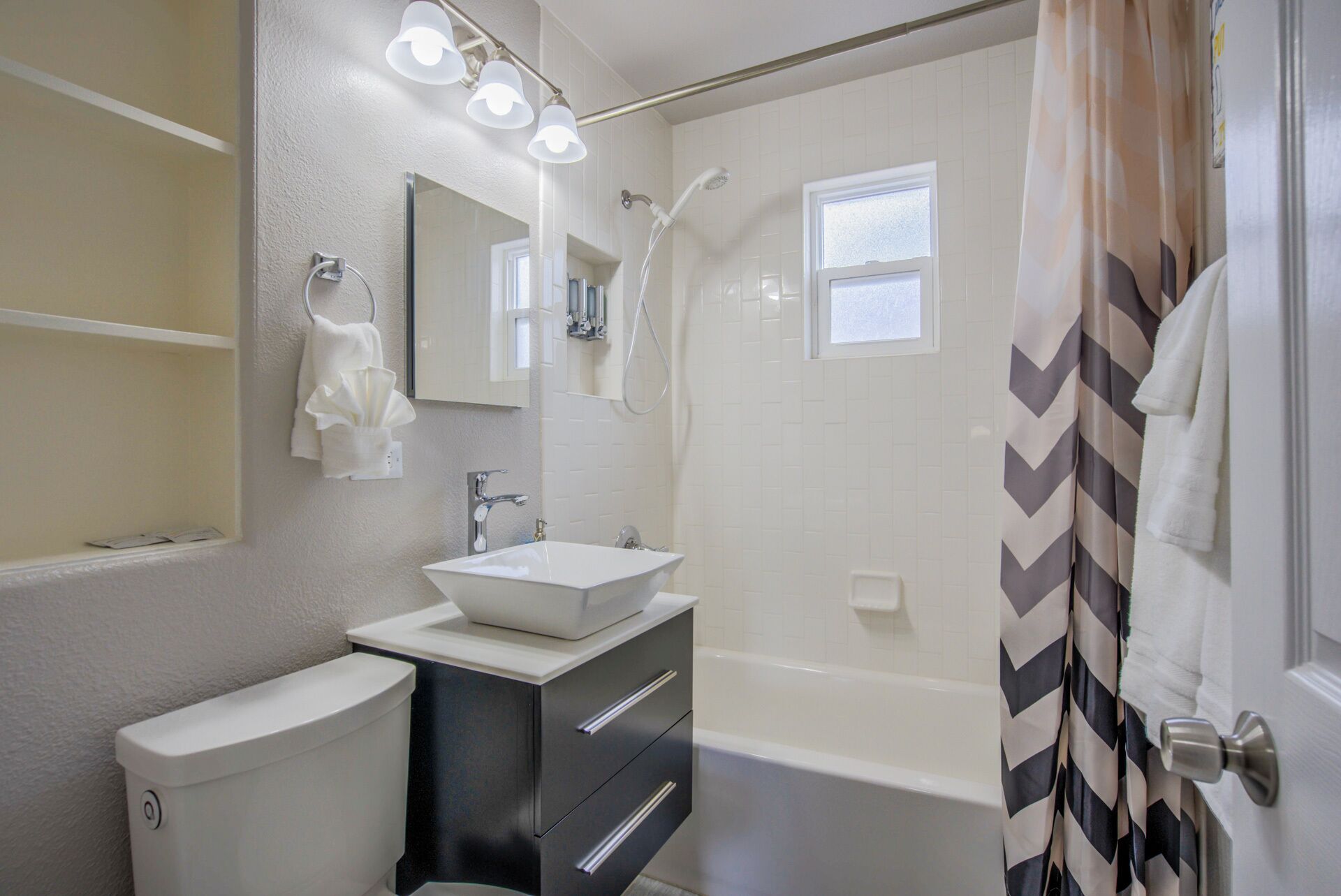 Une salle de bain moderne avec un lavabo blanc, un meuble-lavabo et une baignoire.