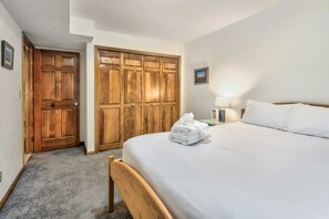 Ein Hotelzimmer mit einem großen Bett, einem Holzschrank, einem Nachttisch mit Lampe sowie einem auf dem Bett gefalteten Handtuch.