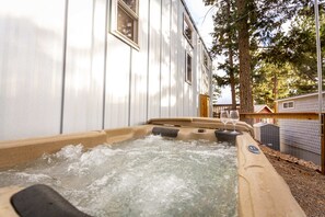 Una vasca idromassaggio con acqua, un pontile in legno e un edificio bianco con finestre.