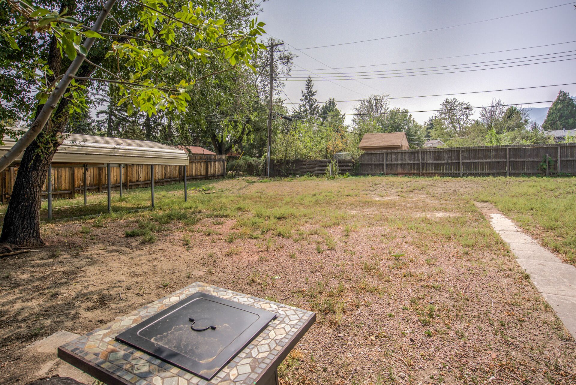 A backyard with a covered patio, a fenced area, and a small garden.
