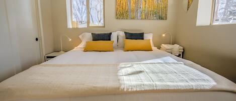 Ett sovrum med en stor säng, två sänglampor, ett fönster och en tavla på väggen.