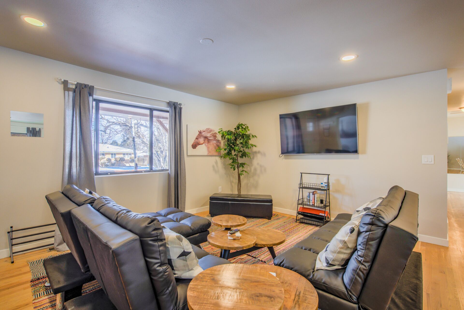 A modern living room with leather sofas, a coffee table, and a TV mounted on the wall.