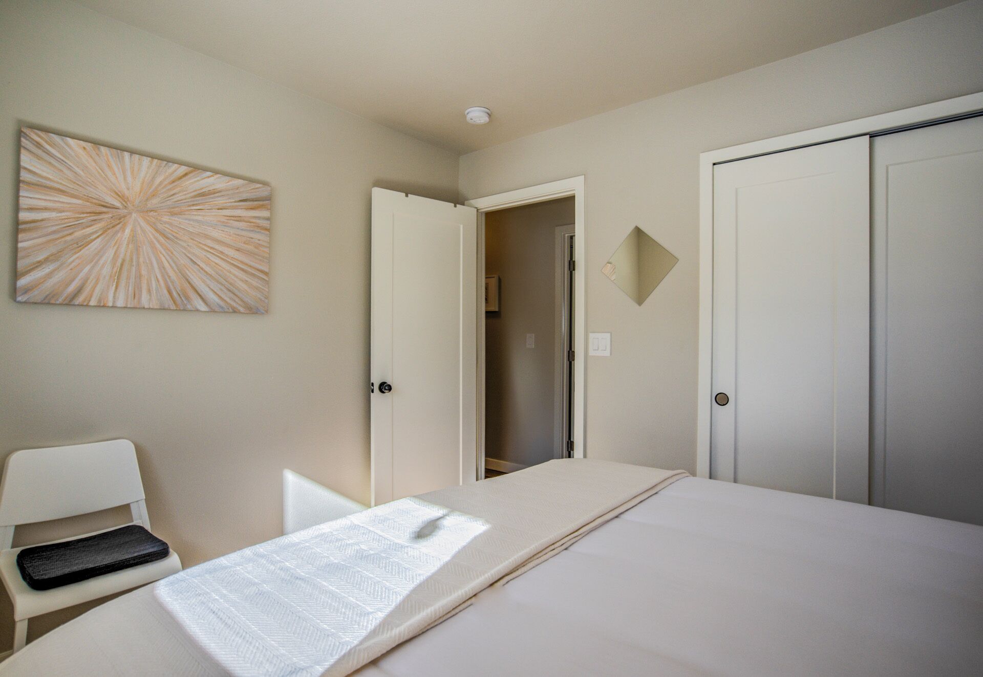 Quarto de hotel com uma cama, uma cadeira, uma porta e uma obra de arte na parede.