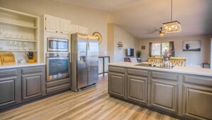 A modern kitchen with a built-in oven, refrigerator, and a dining area with a table and chairs.