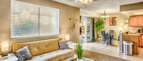 A living room with a sofa, a glass coffee table, and a ceiling fan.