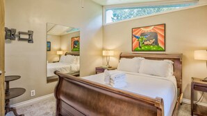 Una camera d'albergo con un letto grande, una scrivania, una sedia, uno specchio e opere d'arte alle pareti.