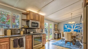 Una cucina moderna con mobili in legno, elettrodomestici in acciaio inossidabile e un'area pranzo con un quadro astratto blu.