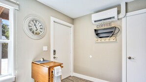 A hallway with a wooden table, a clock, and an air conditioning unit labeled 'COFFEE'. - 1brmodern & Chicdowntown OCC (Colorado Springs)