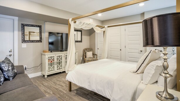 A bedroom with a bed, a TV, a wardrobe, a chair, and a bedside table. - 1brmodern & Chicdowntown OCC (Colorado Springs)