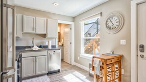 A kitchen with white cabinets, a wooden table, and a clock on the wall. - 1brmodern & Chicdowntown OCC (Colorado Springs)