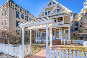 A two-story house with a covered porch and a white picket fence.