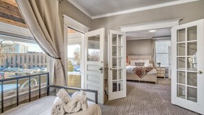 Ein Hotelzimmer mit einem grossen Bett, einem separaten Schlafzimmer mit Fenster und einem Balkon mit Blick auf die Stadt.