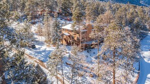 A lodge surrounded by snow-covered trees and mountains.