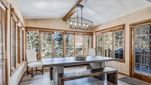 A dining area with a large table, benches, and a chandelier.