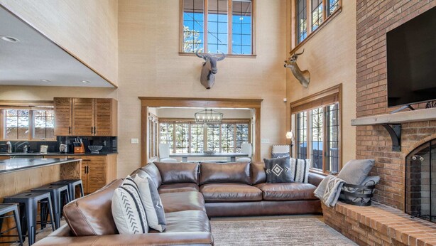 A spacious living area with a large sectional sofa, a fireplace, and a kitchen area visible through an open doorway.