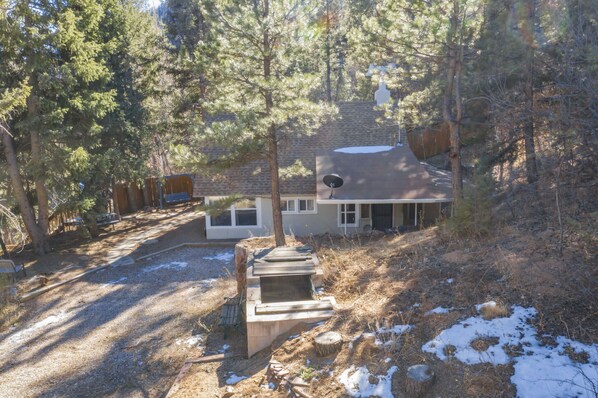 A house surrounded by trees with a satellite dish on the roof.