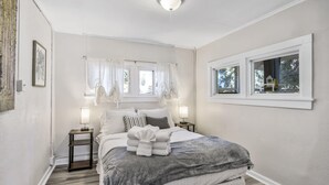 A bedroom with a bed, bedside tables, and a window with curtains.