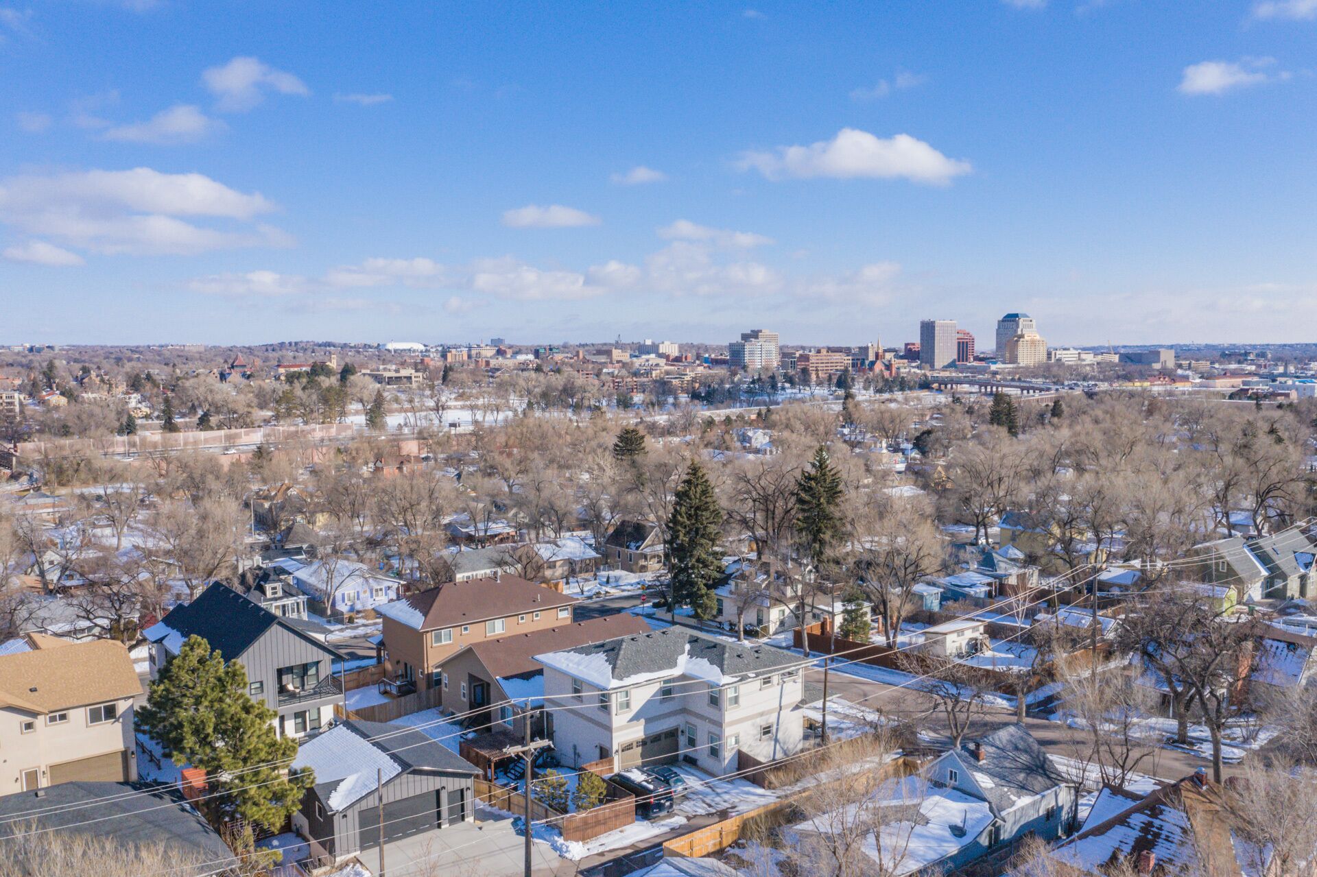 A residential area with houses, trees, and a distant city skyline.