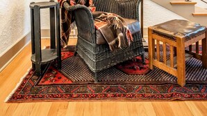 A cozy living room with a wicker sofa, a small wooden table, and a patterned rug. A staircase with a railing leads to an upper level. - 5BD Houseblocks From Broadmoor Fireplacecheyenne Canon & Gorgeous Views! (Colorado Springs)