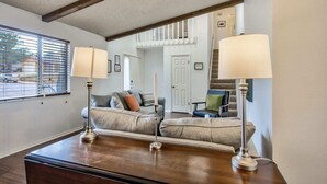 Un salon avec un canapé, deux lampadaires et une vue sur un escalier.