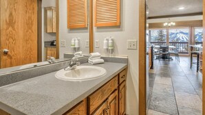 A bathroom with a granite countertop, wooden cabinets, a large mirror, and a view of a dining area with a table and chairs. - 3brbreckenridge Townhomebalcony Mtn Views Hot Tub (Breckenridge)