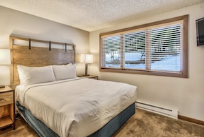 A hotel room with a large bed, two bedside tables, a wooden headboard, a window with blinds, and a thermostat on the wall. - 3brbreckenridge Townhomebalcony Mtn Views Hot Tub (Breckenridge)