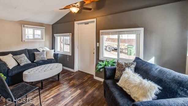 A cozy living room with a dark grey sofa, a tufted ottoman, and a ceiling fan. - 3BR Manitou Springs2min to Restaurants W/hot Tub! (Manitou Springs)