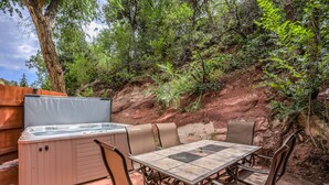 An outdoor patio with a hot tub, a table, and chairs. - 3BR Manitou Springs2min to Restaurants W/hot Tub! (Manitou Springs)