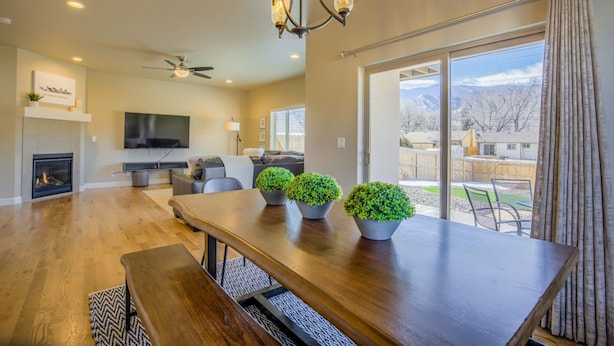 A spacious living room with a fireplace, a flat-screen TV, a ceiling fan, and a large dining table with benches. - 8BD Mnt Viewsgarden Of The Godslarge Groups (Colorado Springs)