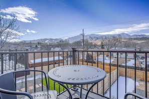 Een balkon met een tafel en stoelen, met uitzicht op een besneeerd landschap met bergen in de verte.