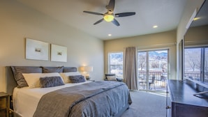 A bedroom with a large bed, a ceiling fan, a desk, and a view of a snowy landscape. - 8BD Mnt Viewsgarden Of The Godslarge Groups (Colorado Springs)