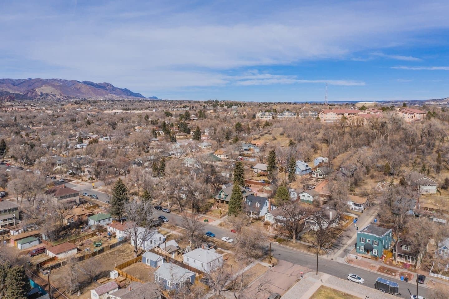 An aerial view of a residential area with houses, roads, and a mountain range in the background.