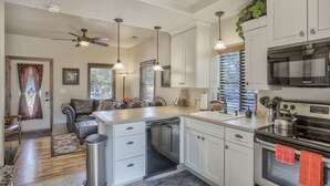 A modern kitchen with white cabinets, stainless steel appliances, and a central island. - 2brdowntown Occmountain Views & Grill (Colorado Springs)