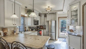 A modern kitchen with white cabinets, stainless steel appliances, and pendant lighting. - 2brdowntown Occmountain Views & Grill (Colorado Springs)
