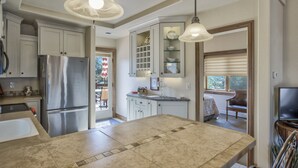 A kitchen with a central island, stainless steel refrigerator, and pendant lighting. - 2brdowntown Occmountain Views & Grill (Colorado Springs)