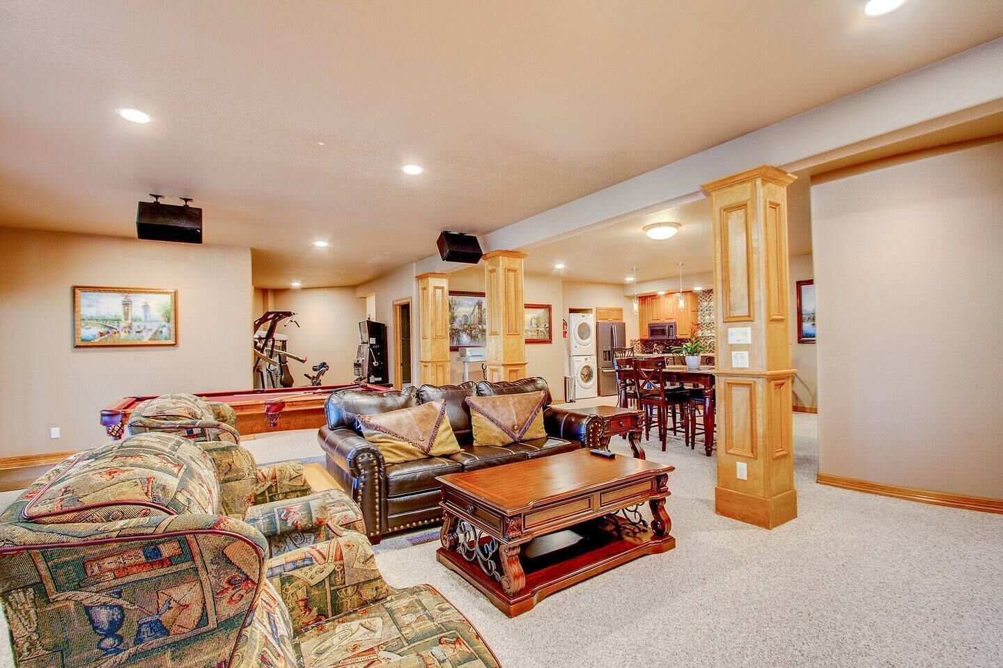 A spacious living room with a pool table, a leather sofa, and a dining area with wooden furniture.