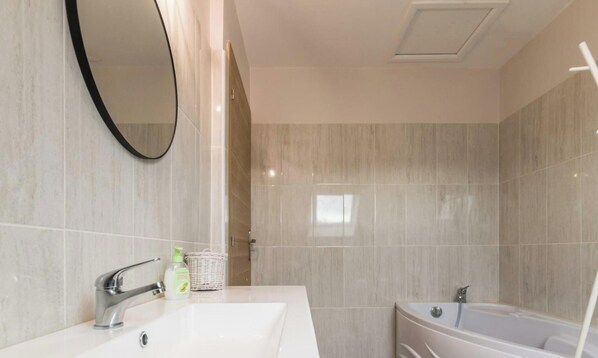 Un baño moderno con un lavamanos grande, un espejo, una bañera y una zona de ducha.