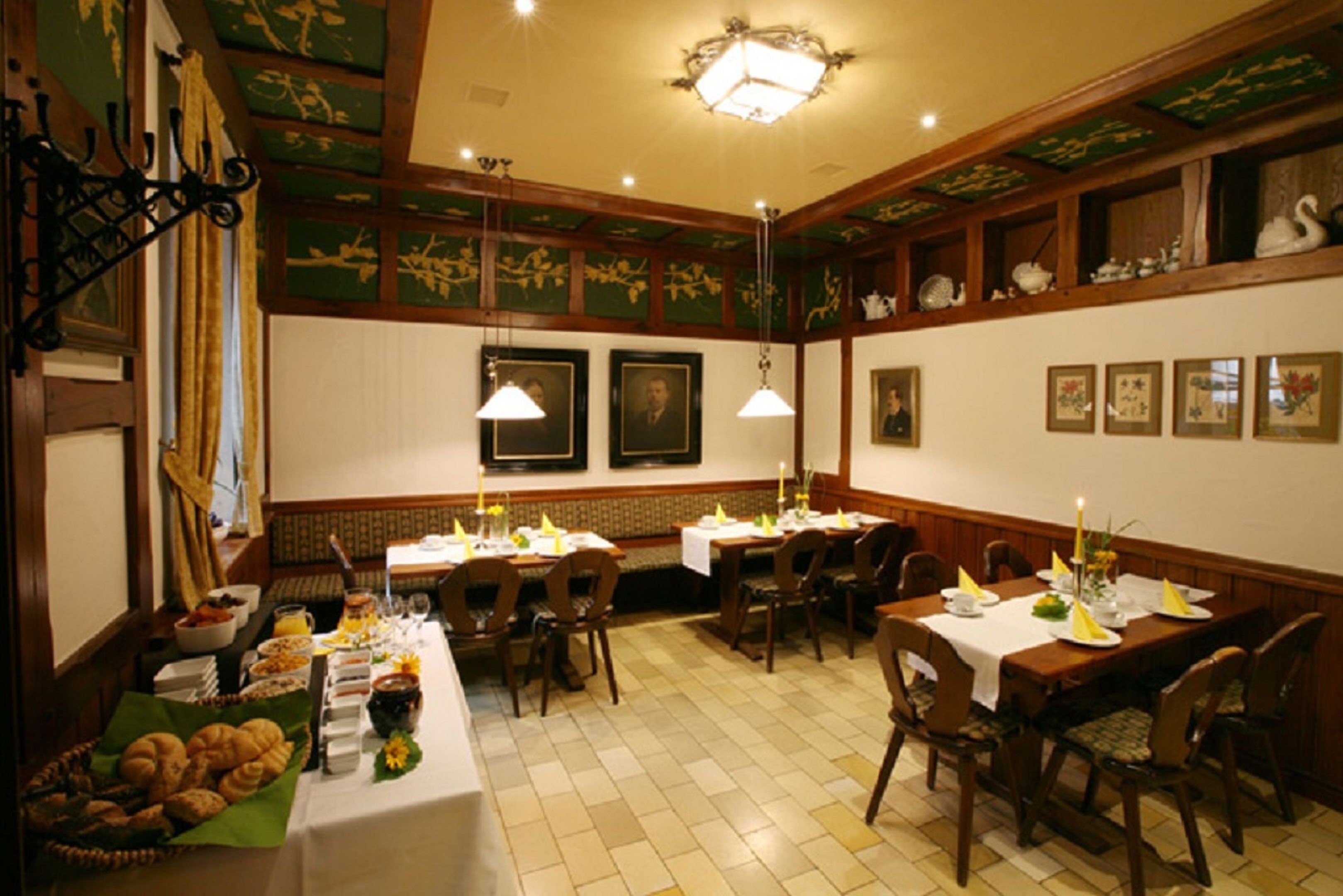 Un comedor con mesas dispuestas para comidas, un bufé con diferentes opciones de alimentos y cuadros en las paredes.