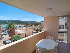 A balcony with a table and chairs, overlooking a marina and buildings.